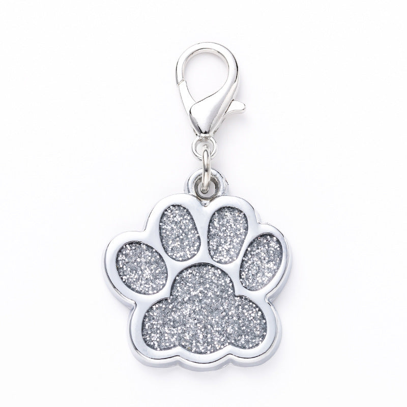 Silver paw print pendant with glittery finish on a white background