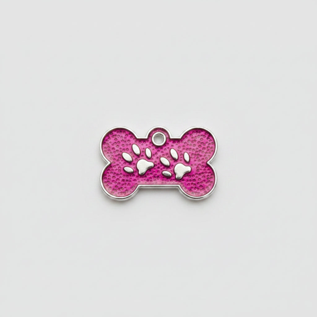 Pink bone-shaped pet tag with paw prints held between fingers