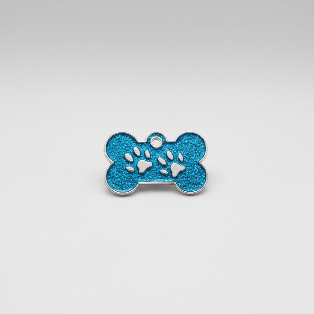 Blue pet tag with paw prints held by a hand on a white background