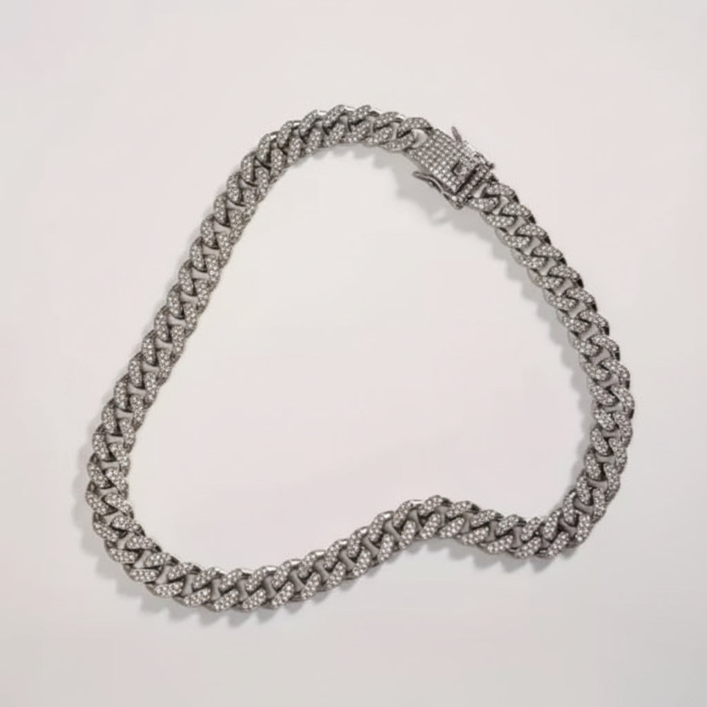 Silver necklace displayed on a white surface with a hand for scale.