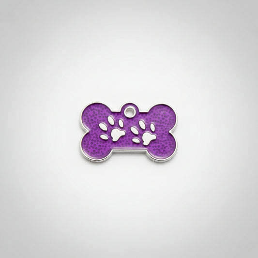 Purple bone-shaped pet tag with paw prints held in a hand