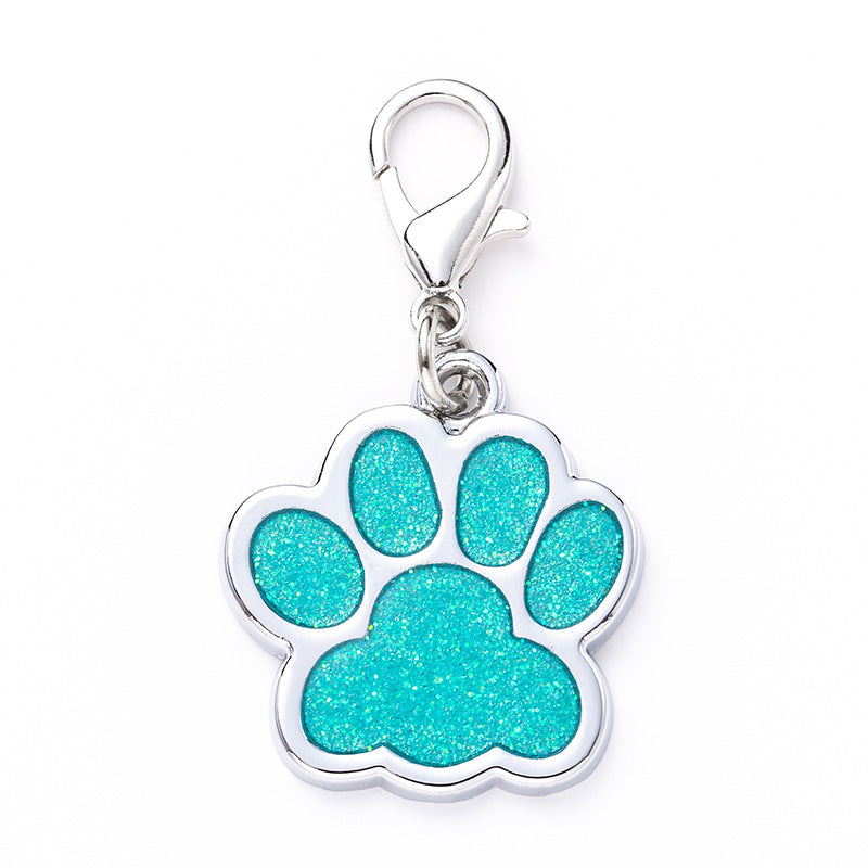 Turquoise glitter paw print charm on a white background